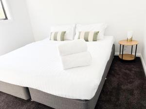 una cama blanca con sábanas y almohadas blancas en Glen’s Fitz St Getaway - Central, en Wagga Wagga 7 fotos más