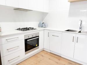 Una cocina blanca con gabinetes blancos y un fregadero. en Glen’s Fitz St Getaway - Central, en Wagga Wagga