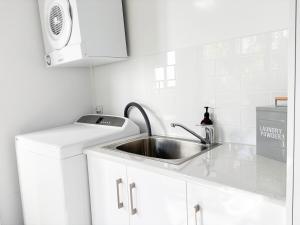 Una cocina blanca con fregadero y microondas. en Glen’s Fitz St Getaway - Central, en Wagga Wagga