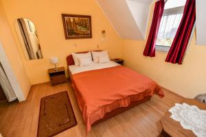 a small bedroom with a bed with orange sheets at Lagúna Panzio Szántód in Szántód