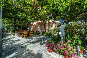 a garden with a table and chairs under an orange tree at Zotos Rooms in Parga