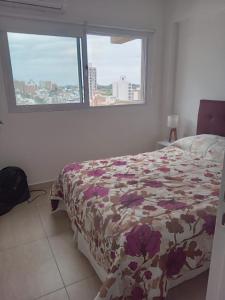 a bedroom with a bed with a floral bedspread and two windows at Departamento macrocentro Santa Fe in Santa Fe