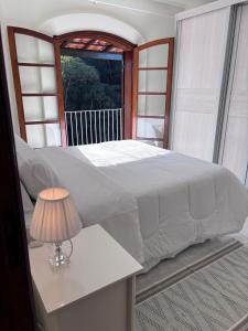a bedroom with a large white bed and a table with a lamp at Casa Refúgio Canto da Viola in São Roque