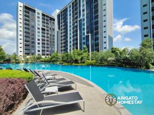 a swimming pool with lounge chairs in front of a building at Friendly Stay SplashMania Fun & Near KLIA Premium Netflix in Bandar Gamuda Cove