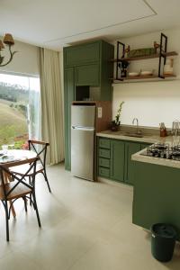 a kitchen with green cabinets and a white refrigerator at Paraíso dos Ipês in Viçosa +30 photos