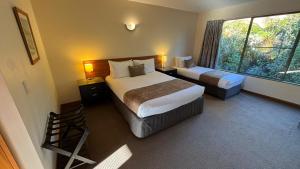 a hotel room with two beds and a window at Punga Grove in Franz Josef
