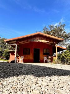 a red house with two white chairs in front of it at Casa de campo Ecos del Poás in Alajuela
