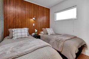 two beds in a bedroom with wood paneled walls at Matapouri Magic - Matapouri Holiday Home in Matapouri