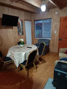 a room with a table and chairs and a television at Cabañas Manolo in Osorno