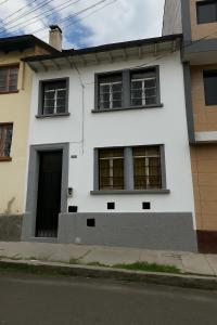 a white house with black windows on a street at Habitación cómoda en Quito in Quito