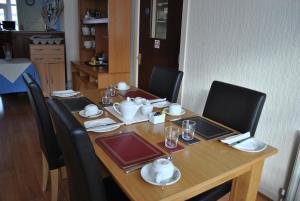 uma mesa de madeira com cadeiras pretas e uma mesa com pratos e pratos em The Address em Blackpool