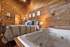 a bathroom with a large white tub in a wooden wall at View Location Studio Log Cabin Hot Tub Fireplace in Pigeon Forge
