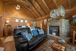 a living room with a leather couch and a fireplace at View Location Studio Log Cabin Hot Tub Fireplace in Pigeon Forge
