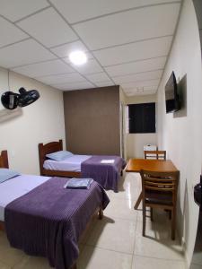 una habitación de hotel con dos camas y una mesa en Hotel malibu, en Muriaé