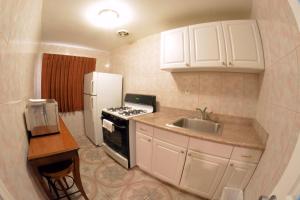a kitchen with white cabinets and a sink and a refrigerator at The Palace Inn in Oxnard