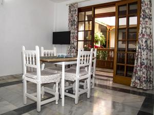 a dining room table with three chairs and a television at Apartamentos Tapahuga in Playa de Santiago