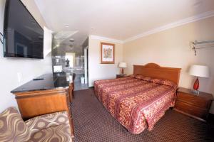 a hotel room with a bed and a flat screen tv at The Palace Inn in Oxnard