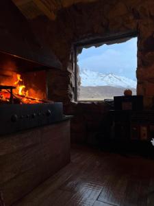 a kitchen with a stove and a window with a view at Cabaña Los Molles in Malargüe +4 photos