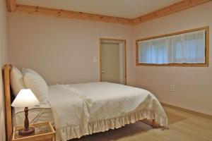 a bedroom with a white bed and a window at Tasha's Garden Private Pension Jeonju Hanok Village in Jeonju