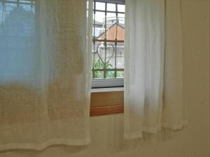 a window with white curtains in front of a window at Tasha's Garden Private Pension Jeonju Hanok Village in Jeonju