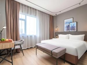 a hotel room with a large bed and a desk at Country Inn & Suite by Radisson, Shanghai Hongkou Football Stadium Chifeng Road in Shanghai +22 photos