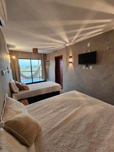 ein Schlafzimmer mit zwei Betten und einem Flachbildfernseher in der Unterkunft Chalé Duplex Beira Mar Macapá in Luis Correia