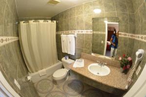 a bathroom with a sink and a toilet and a mirror at The Palace Inn in Oxnard
