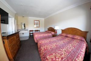 a hotel room with two beds and a bathroom at The Palace Inn in Oxnard
