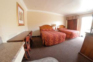 a hotel room with two beds and a desk at The Palace Inn in Oxnard
