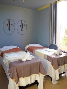 two beds in a room with clocks on the wall at Pestana Bahia Praia Nature & Beach Resort in Vila Franca do Campo