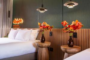 a hotel room with a bed and two vases with flowers at Calle Flora Hotel by Jalo in Medellín