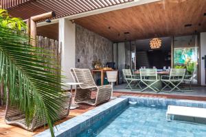 a patio with a pool and chairs and a table at Casa Bangalô dos Milagres in Passo de Camarajibe
