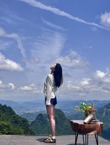 a woman standing on a table looking at the mountains at Cloudspire Haven-Cliffside Coffee-Beautiful Sunrise in Zhangjiajie