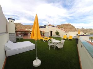 a patio with a table and chairs and an umbrella at Apartamentos Tapahuga in Playa de Santiago