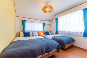 a bedroom with two beds and a window with blue curtains at Third Place Tokyo - Aoto - in Tokyo