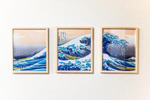 four framed pictures of the wave on a wall at Third Place Tokyo - Aoto - in Tokyo