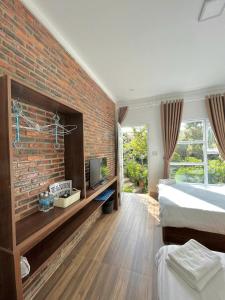 ダラットにあるHomestay Guitar Houseのレンガの壁のベッドルーム、ベッド、テレビが備わります。