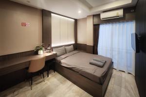 a bedroom with a bed and a desk and a window at Max Residence in Pattaya