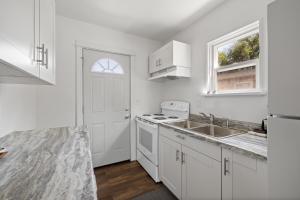 Una cocina blanca con fregadero y estufa. en The Holcomb House, en Rapid City 9 fotos más