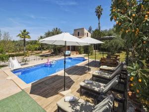 ein Pool mit Stühlen und einem Sonnenschirm und einem Orangenbaum in der Unterkunft Nice holiday home with private pool in Manacor