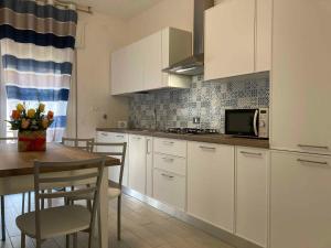 a kitchen with white cabinets and a table with a microwave at Apartment in Rosolina Mare 49216 in Rosolina Mare