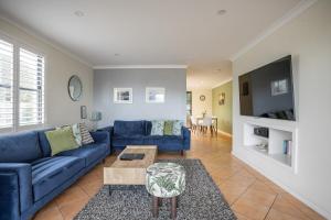 a living room with a blue couch and a table at Albany Harbourside Apartments And Houses in Albany