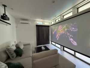 una gran pantalla en la sala de estar con sofá en 御宿ガーデンヴィラ, en Onjuku