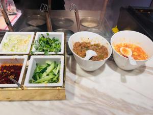 a table topped with bowls of food and vegetables at Atour Light Harbin Central Street in Harbin