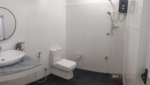 a white bathroom with a toilet and a sink at Cealora Resort in Dambulla