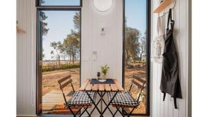 a patio with a table and chairs on a porch at Pine Hill Tiny House by Tiny Away in Wangoom