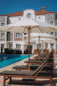 eine Reihe von Stühlen mit Sonnenschirmen neben einem Pool in der Unterkunft Lamer Sea Breeze Resort in Baku