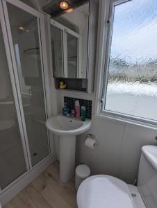 a bathroom with a sink and a shower and a toilet at Pet-Free Swift Burgundy Family Holiday Home at Littlesea Holiday Park, Weymouth in Wyke Regis