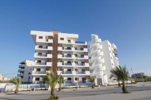 a white apartment building with palm trees in front of it at Arenales Playa Superior by Mar Holidays in Arenales del Sol