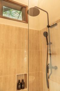 une douche avec pommeau de douche dans une salle de bain dans l'établissement Uluwatu Ocean Front Surf Suite, à Uluwatu